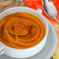 Creamy pumpkin soup with swirled orange and brown hues.