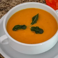 Creamy orange soup garnished with fresh herbs.