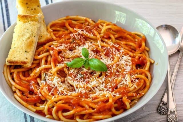 A serving of pasta with roasted tomato sauce, topped with parmesan cheese and basil.