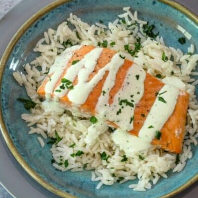 a salmon fillet on a bed of rice with a drizzle of basil mayonnaise.