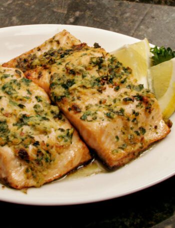 salmon on a plate with lemons, and herbs