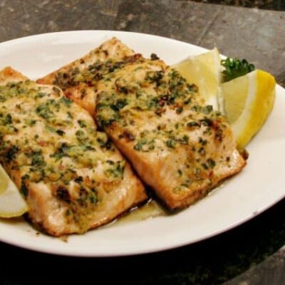 salmon on a plate with lemons, and herbs