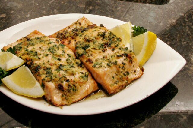 salmon on a plate with lemons, and herbs