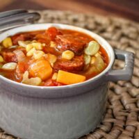 A ramekin with a serving of butternut squash and smoked sausage stew.
