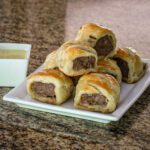 sausage rolls on a plate with a mustard dip on the side