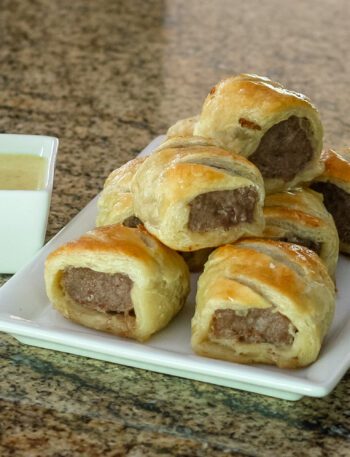 sausage rolls encased in puff pastry on a serving plate