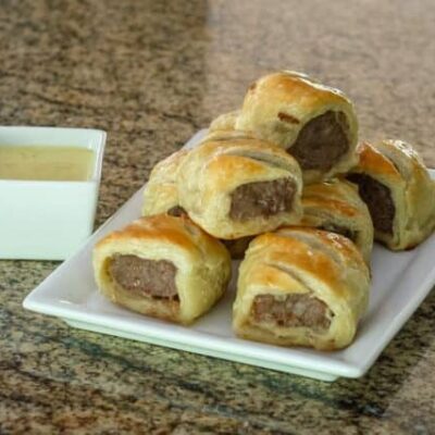 sausage rolls encased in puff pastry on a serving plate