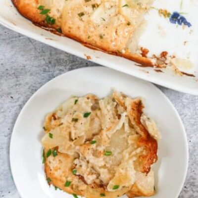 scalloped potatoes on a small plate beside the baking dish