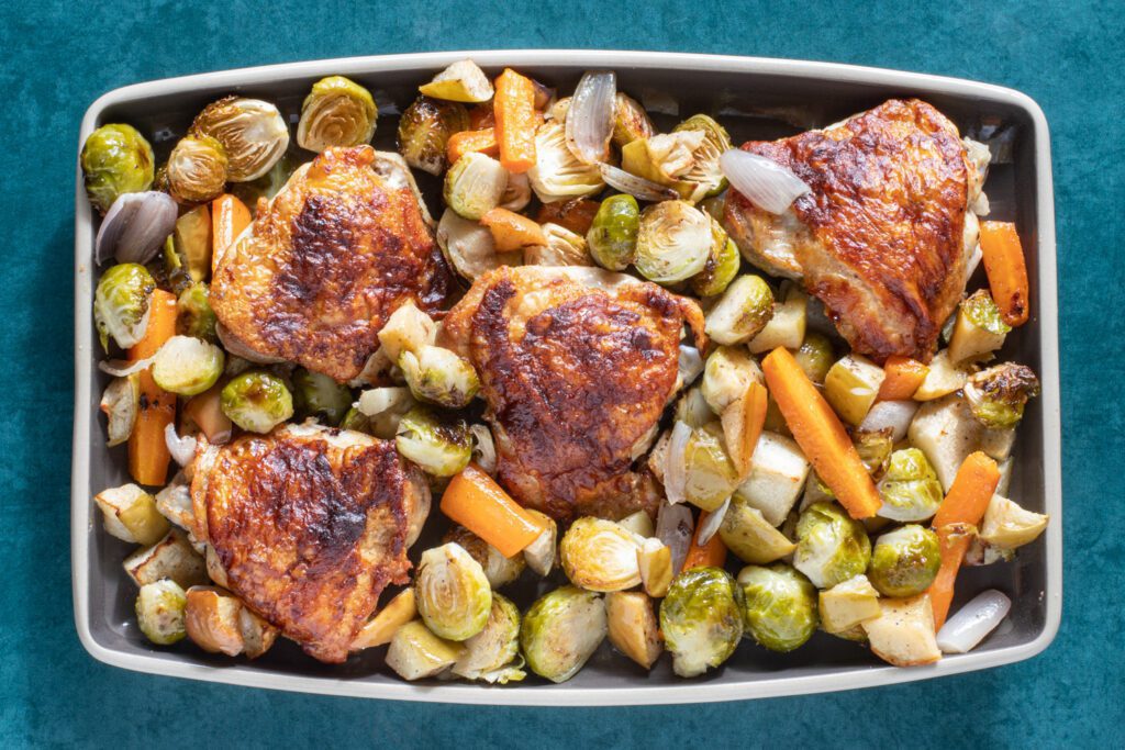 a platter with the sheet pan chicken thighs, brussels sprouts, apples, and more.