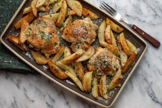 Sheet pan chicken thighs and potatoes on a serving tray