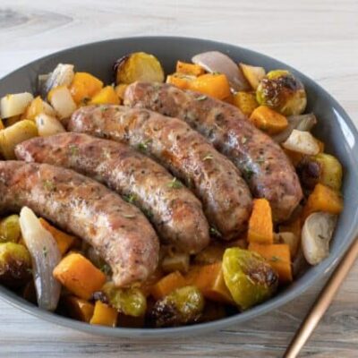 Sausages and fall vegetables on a plate.