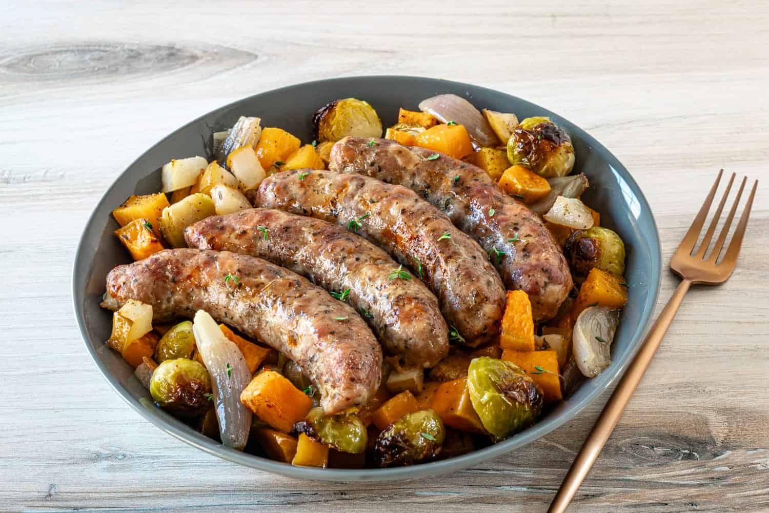 Succulent grilled sausages with roasted vegetables on a gray plate.