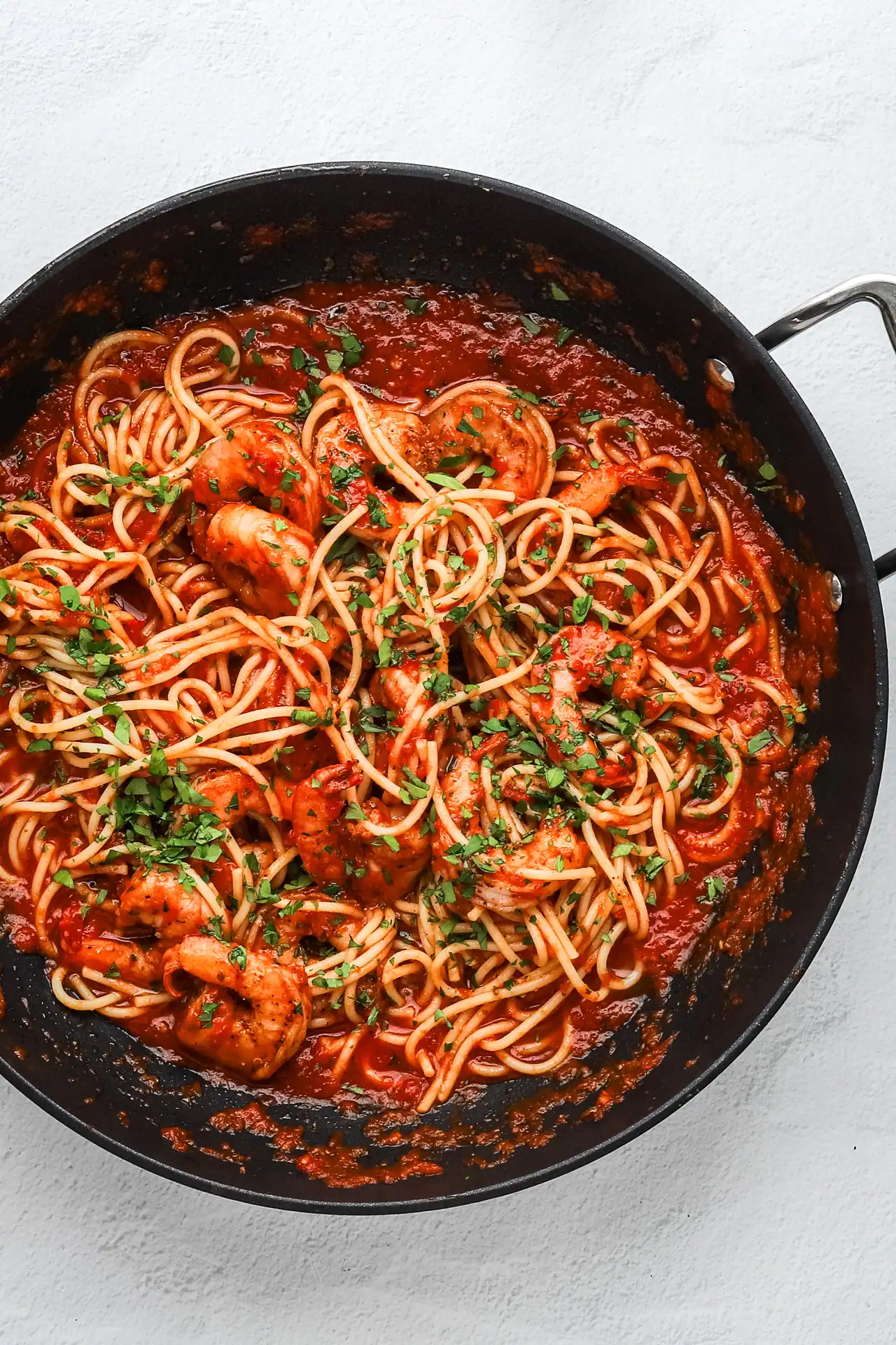 Spaghetti with shrimp and tomato sauce garnished with chopped parsley.
