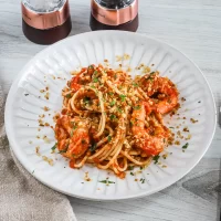 Succulent shrimp and spaghetti garnished with herbs and breadcrumbs.