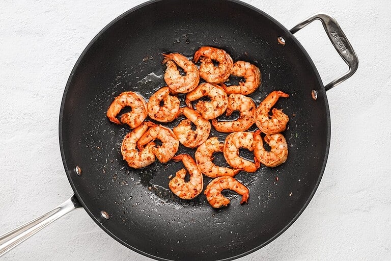 Cooked seasoned shrimp in a black skillet, ready to serve.
