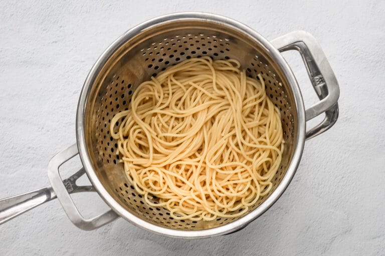 Cooked spaghetti pasta in a stainless steel colander.