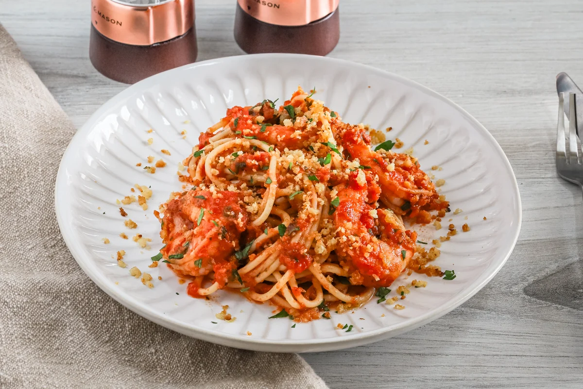 A plate of shrimp fra diavolo with crispy garlic breadcrumbs and parsley topping.
