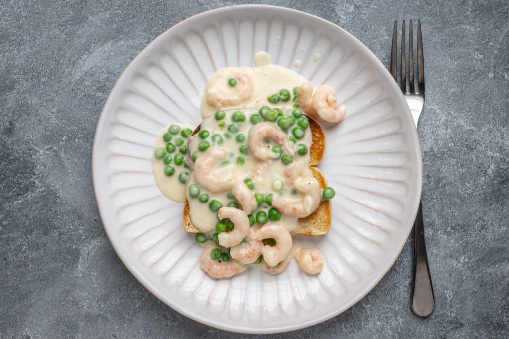 a plate of shrimp wiggle with peas and rich sauce