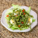 green bean salad on a lettuce lined plate with hard boiled eggs