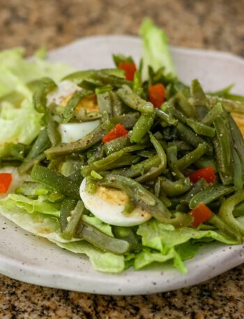 a simple green bean salad on a lettuce-lined plate