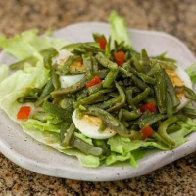 a simple green bean salad on a lettuce-lined plate