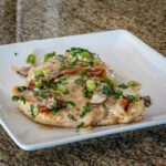 chicken with green onions, bacon, and sour cream sauce on a serving plate