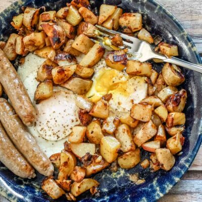 Golden roasted potatoes and fried eggs on a rustic plate.