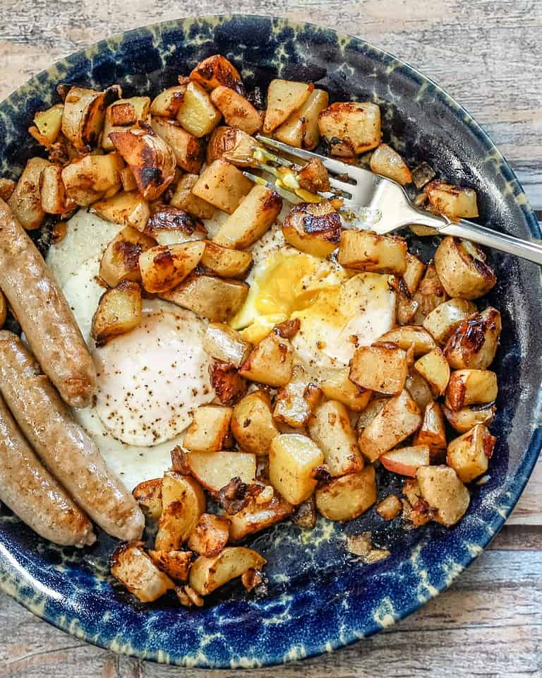 Golden roasted potatoes and fried eggs on a rustic plate.