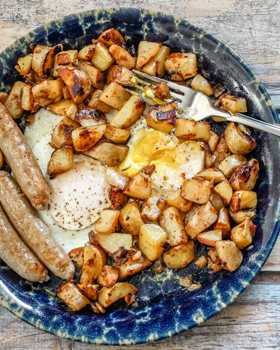 Golden roasted potatoes and fried eggs on a rustic plate.