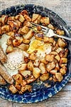 A plate of delicious golden brown home fries with eggs and sausages.