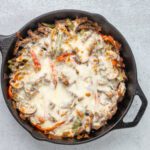 philly cheesesteak in a skillet with cheese topping