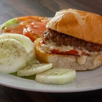 sliders with remoulade sauce on a plate with cucumbers and tomatoes