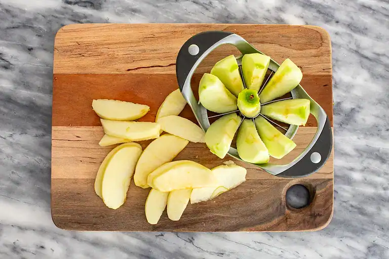 Sliced green and yellow apples on a wooden cutting board.