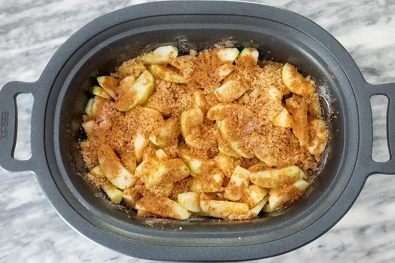 Fresh sliced apples with cinnamon sugar topping in a slow cooker.