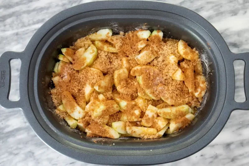 Fresh sliced apples with cinnamon sugar topping in a slow cooker.