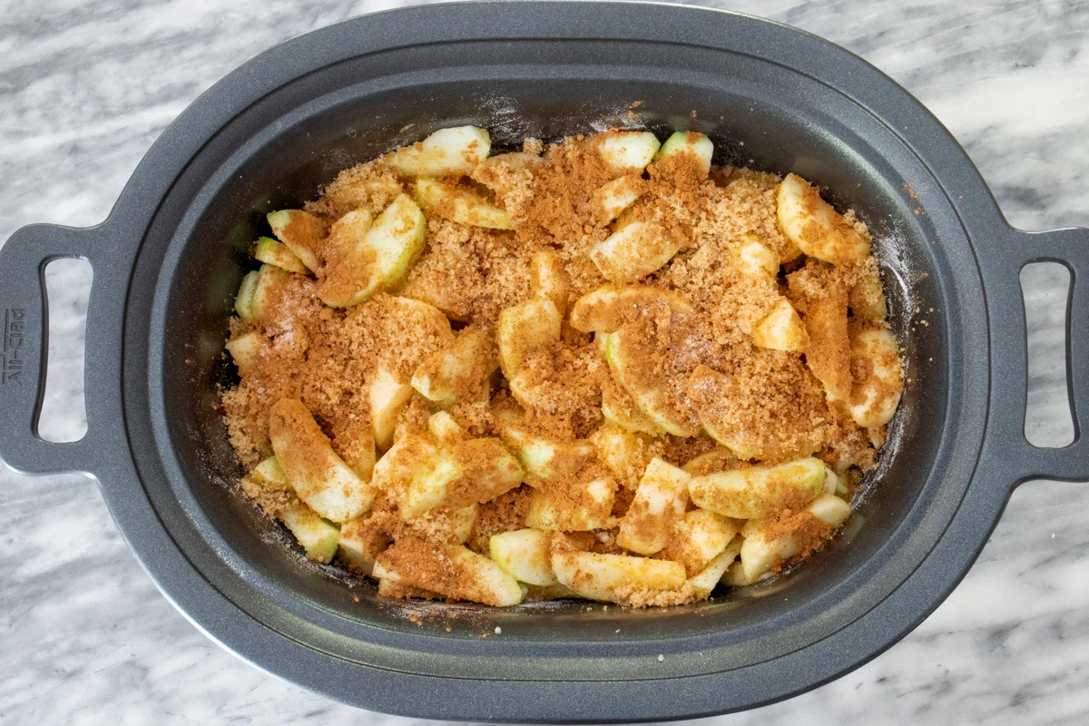 Slow cooker apple butter prep: sliced apples, brown sugar, and spices in the crock pot.