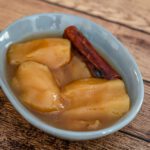 a dessert dish with slow cooker apples and a cinnamon stick