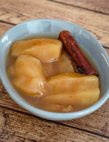 slow cooked apples in a small dish with a cinnamon stick