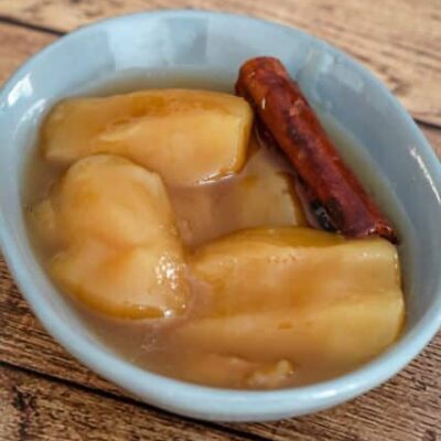 slow cooked apples in a small dish with a cinnamon stick