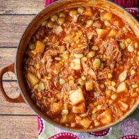 A bowl of rich and delicious Brunswick stew with corn muffins on the side.