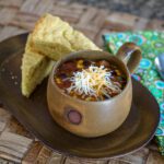 chicken enchilada soup on a serving tray with cornbread wedges