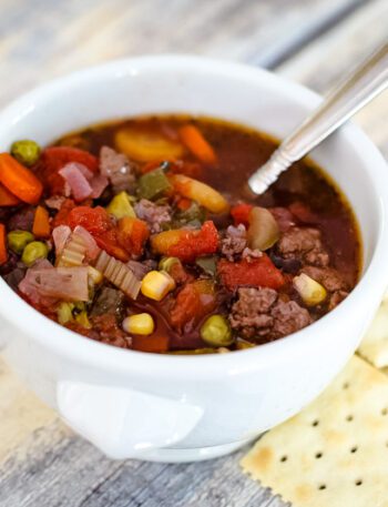slow cooker hamburger soup in a bowl with crackers on the side.