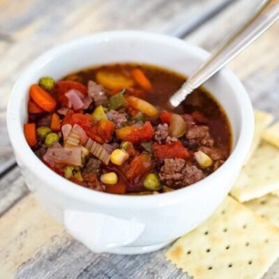 slow cooker hamburger soup in a bowl with crackers on the side.