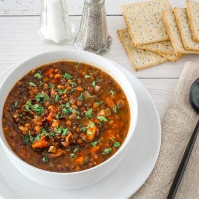A bowl of slow cooker lentil soup with crackers.