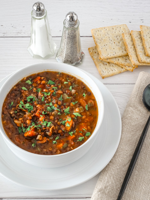 A bowl of slow cooker lentil soup with crackers.