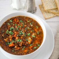 A bowl of slow cooker lentil soup with crackers.