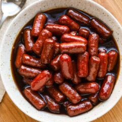 Sweet glazed sausages with rich sauce in a white bowl.