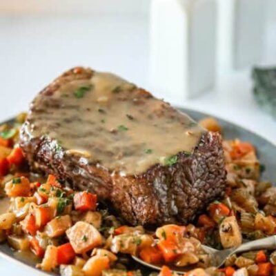 slow cooker pot roast and gravy surrounded by diced vegetables.