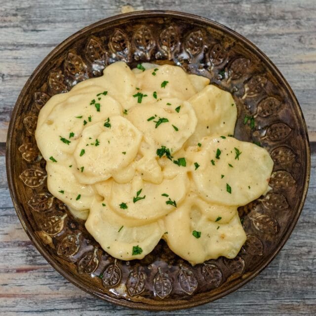 A plate of slow cooker scalloped potatoes with cheese.