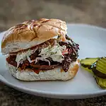 Smoked brisket sandwich with shredded cabbage slaw on a toasted bun.